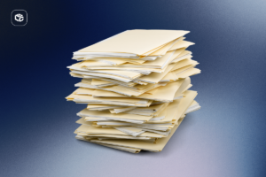 Pilha alta de documentos e pastas de papel organizadas de forma irregular sobre uma superfície lisa. Os arquivos estão empilhados verticalmente, formando uma coluna de papéis em tons claros. O fundo apresenta um gradiente nas cores azul escuro e cinza, com iluminação suave que destaca o volume e a quantidade de documentos. No canto superior esquerdo há um pequeno logotipo branco dentro de um quadrado com cantos arredondados.